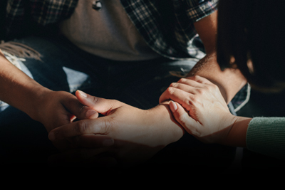 two hands clasped in support and reassurance during a difficult moment focusing on connection and healing relationships among seven friends